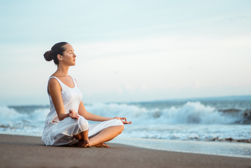 mujer en la playa meditando
